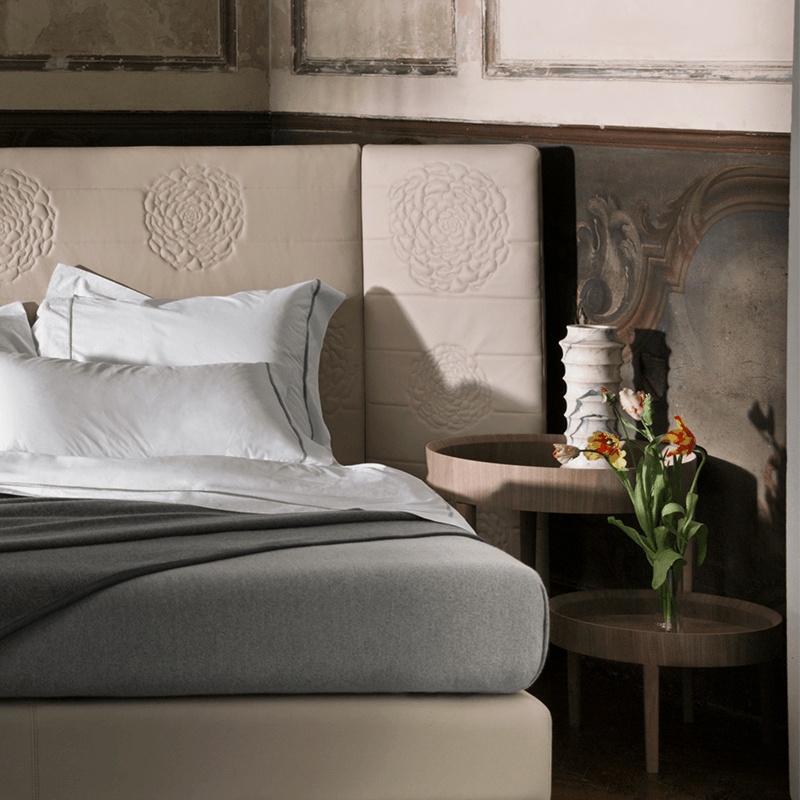 Luxury bed with floral-embroidered headboard, crisp white bedding, and elegant nightstands