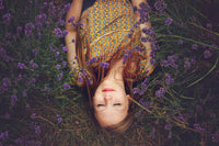 Woman lying in lavender field with relaxed expression, natural outdoor setting