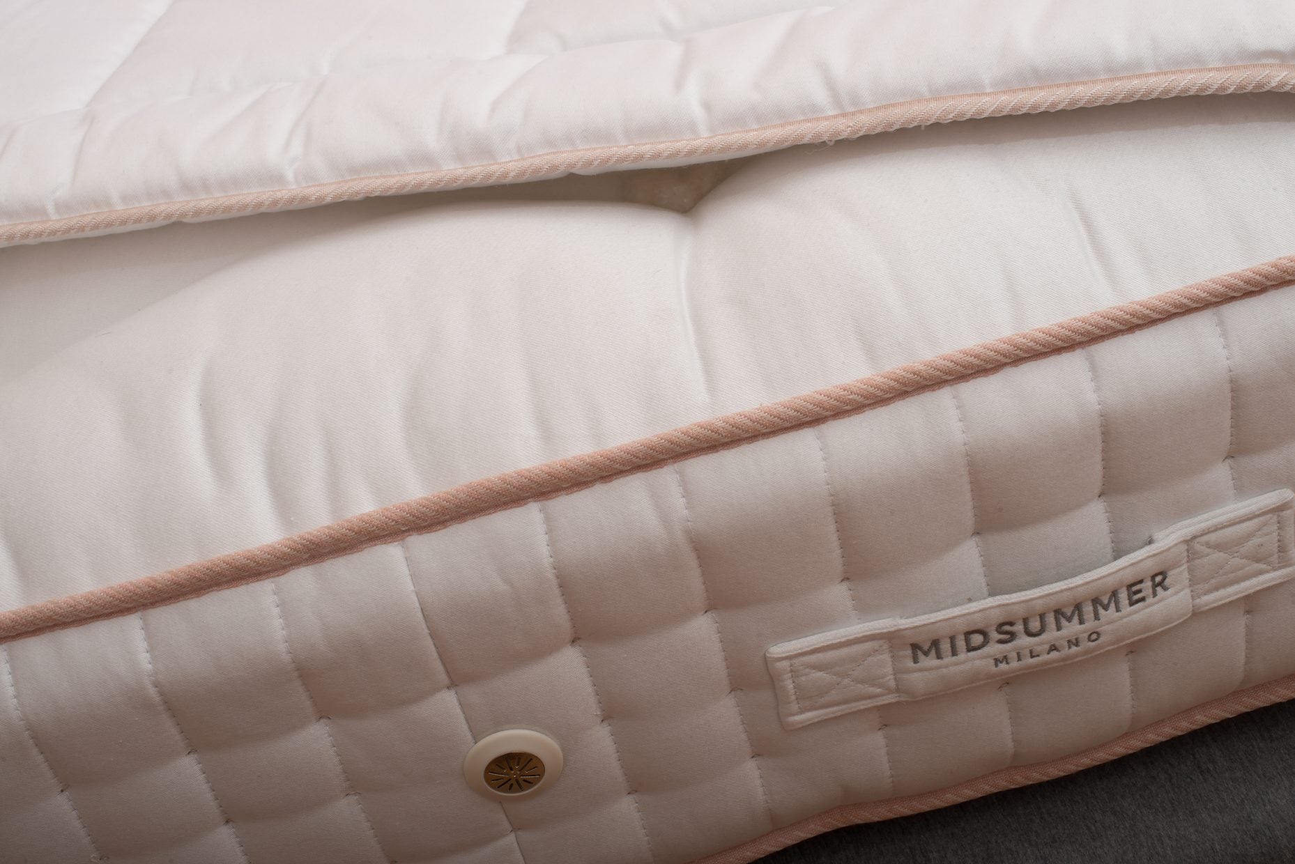 The edge of a mattress, piped and stitched by hand.
