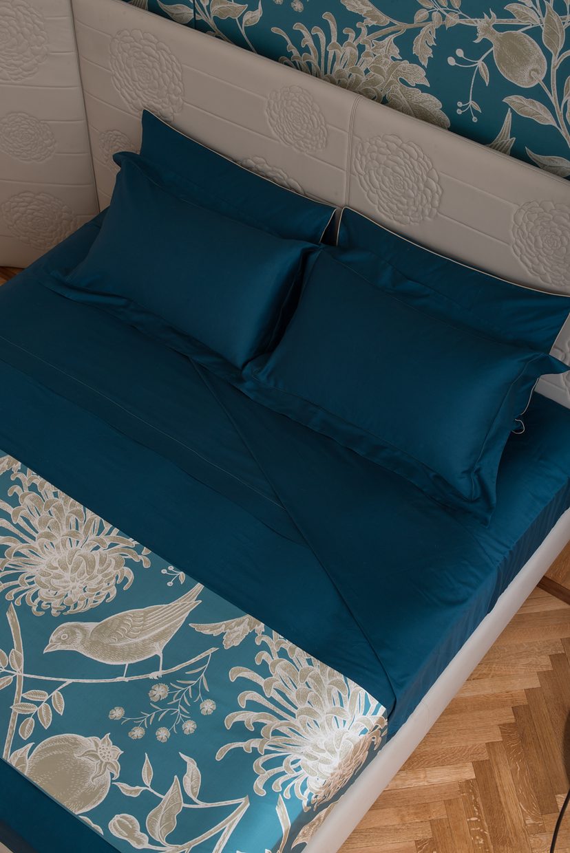 Teal bedding, printed with flowers and birds.