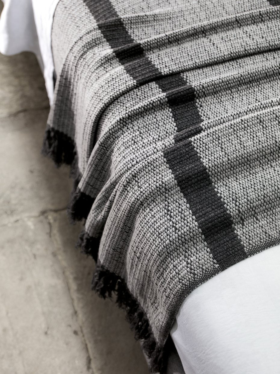 A woven throw at the foot of the bed.