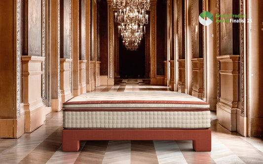 Luxury mattress on red bed frame in ornate hallway with chandeliers and marble floor
