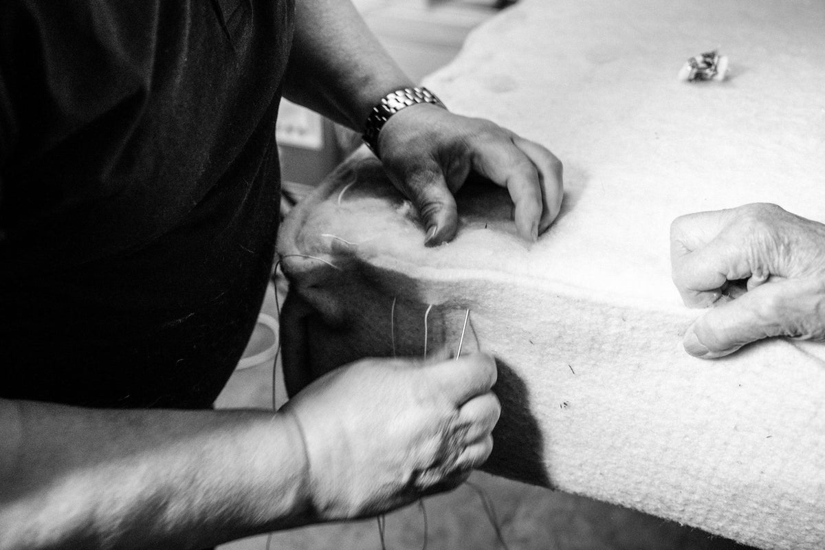 Artisan hand-stitching a luxury mattress with natural materials, close-up view