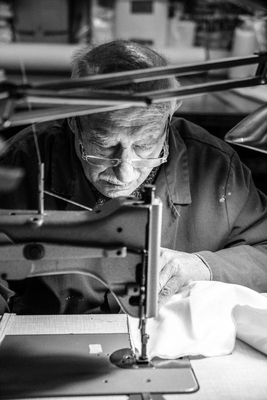 Artisan sewing natural fabric on industrial sewing machine, handmade bedding process