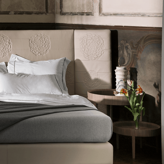 Luxury bed with floral-embroidered headboard, crisp white bedding, and elegant nightstands