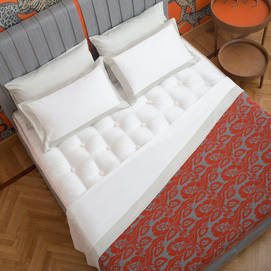 Luxury tufted mattress with white bedding and a red patterned throw on a grey upholstered bed