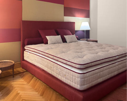 Luxury red upholstered bed with a thick layered mattress and matching pillows.