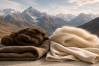 Raw brown and white natural wool fibers on folded fabric against a mountain landscape.