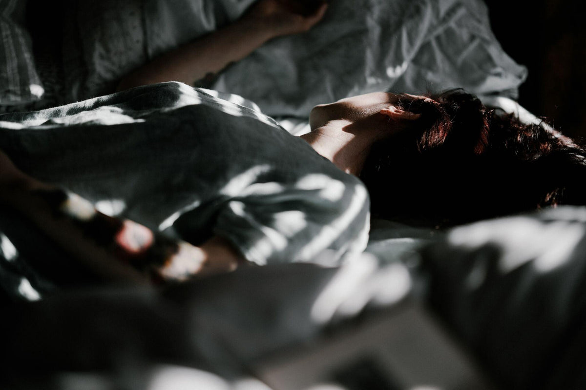Person resting on a bed with soft natural light, showcasing luxury bedding comfort