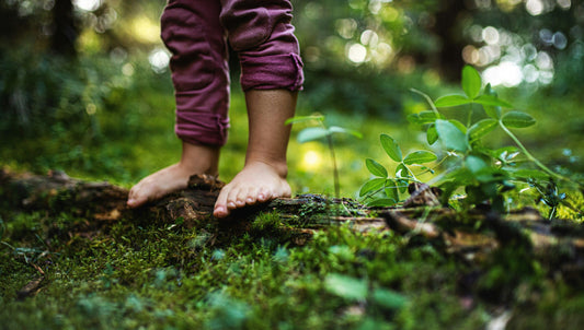 Bare feet and rolled pants on mossy forest floor, natural outdoor setting