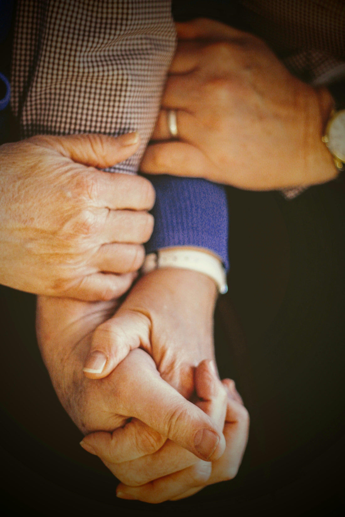 Close-up of two people holding hands, conveying comfort and human connection.