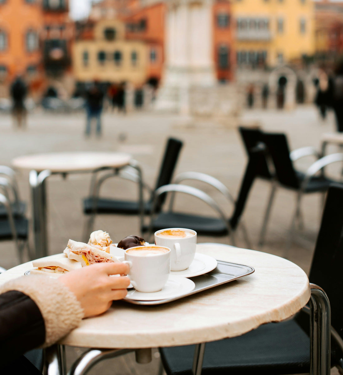 Outdoor café table with cappuccinos and pastries in Italian piazza setting