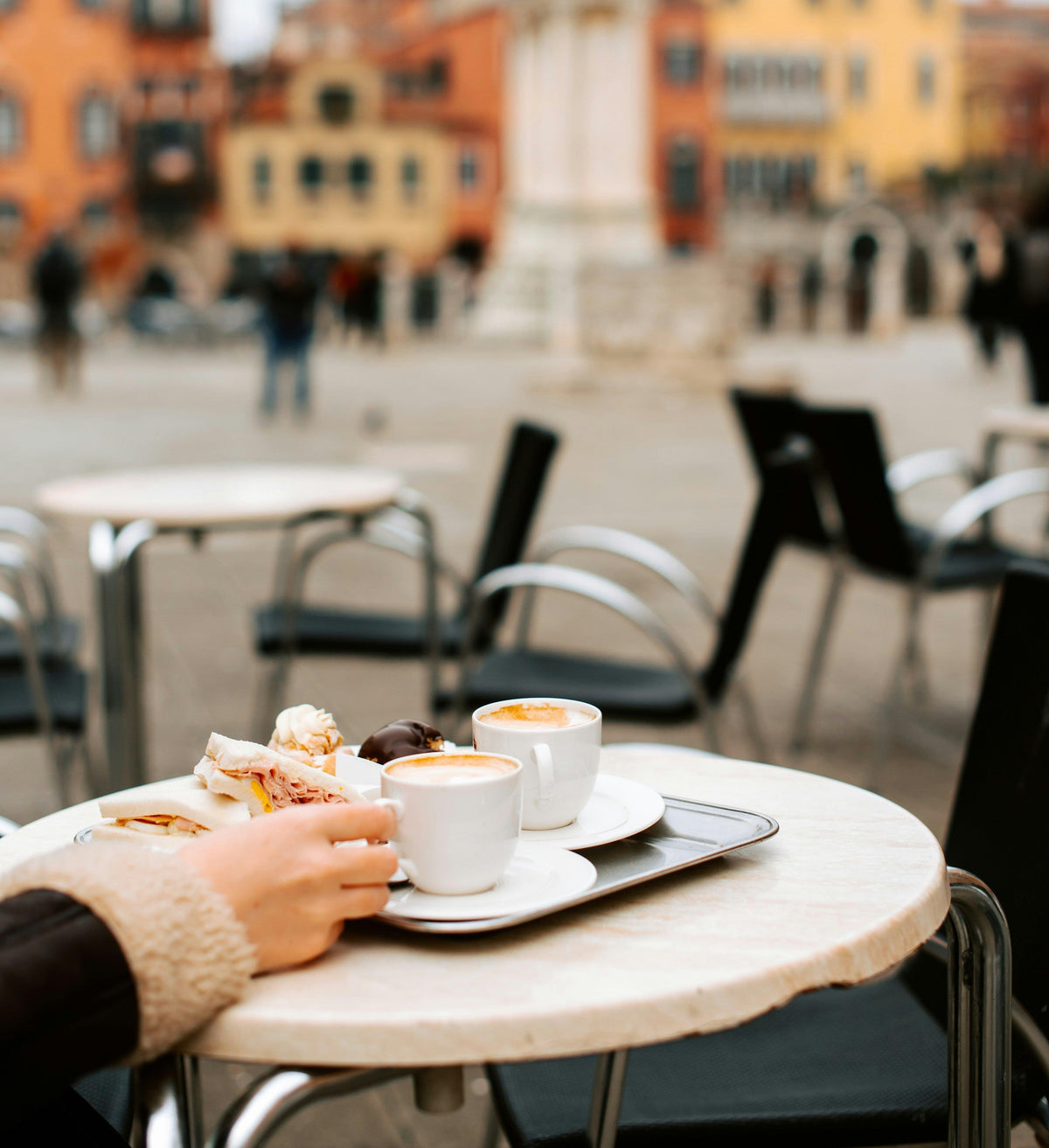 Outdoor café table with cappuccinos and pastries in Italian piazza setting