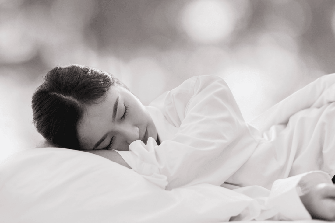 Woman sleeping peacefully on a luxury bed with soft white bedding