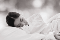 Woman sleeping peacefully on a luxury bed with soft white bedding