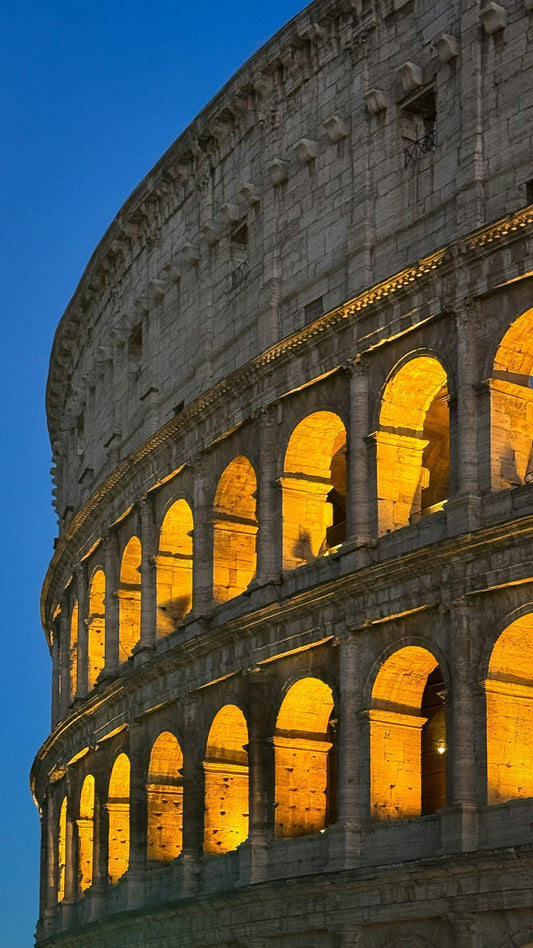 Close-up of illuminated Colosseum arches at dusk, showcasing ancient Roman architecture