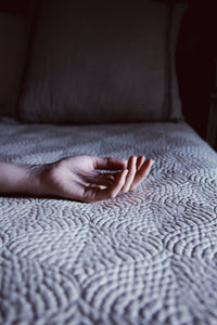 Hand resting on luxury textured bedspread, handmade natural bedding, Italian design