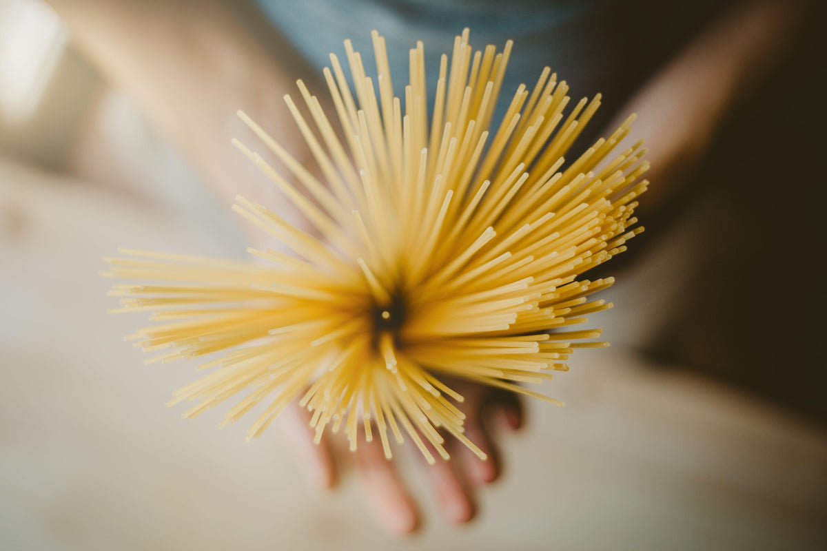 Hand holding a bundle of uncooked spaghetti pasta viewed from above
