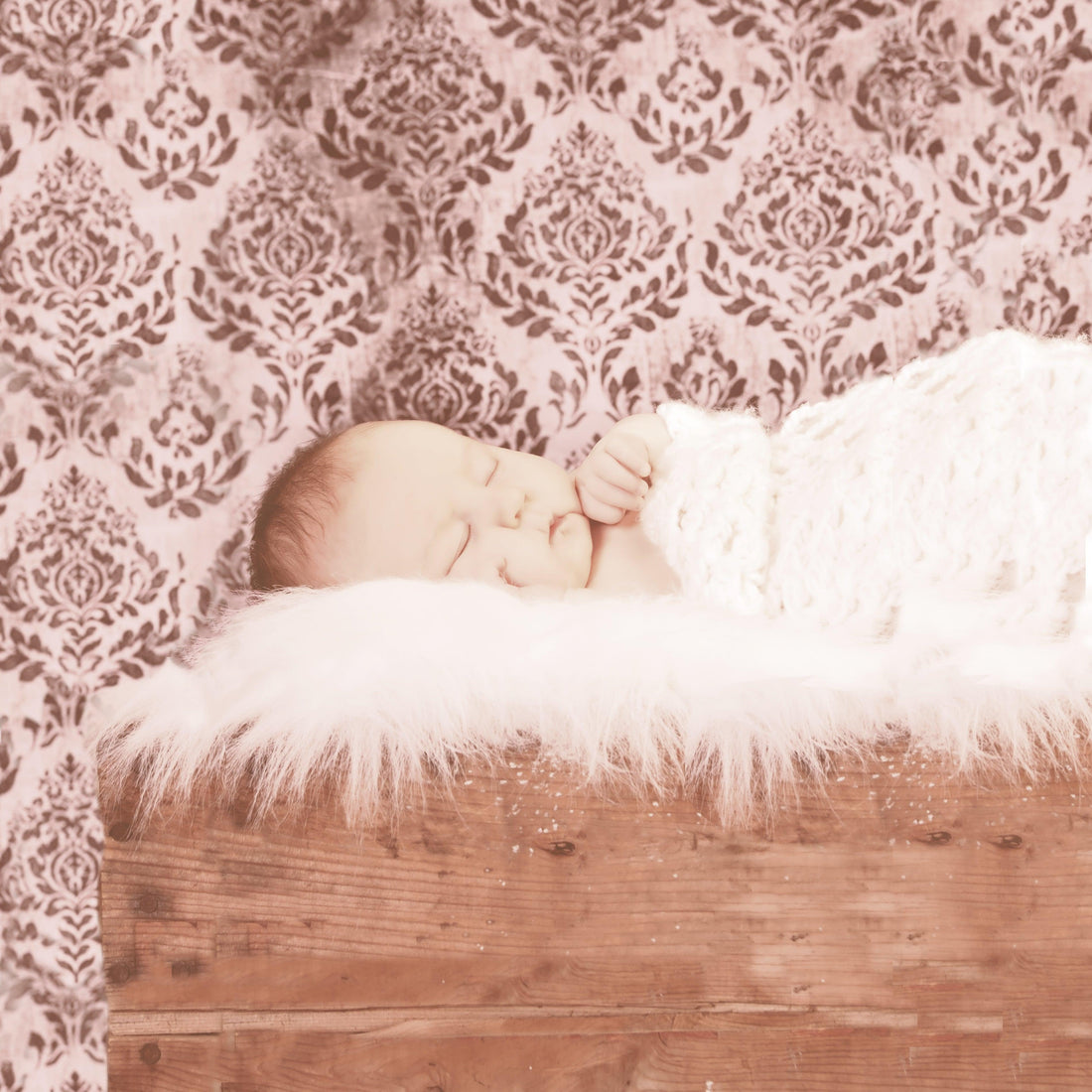 Newborn baby sleeping on fluffy white blanket in wooden bed with ornate wallpaper background