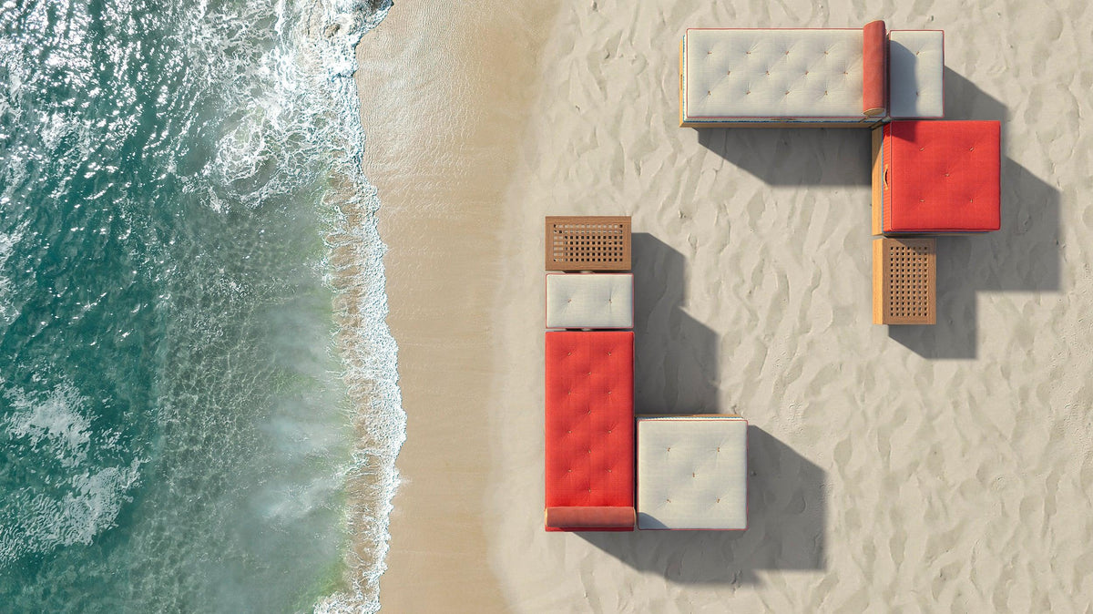 Modular outdoor lounge furniture on sandy beach by ocean waves, viewed from above