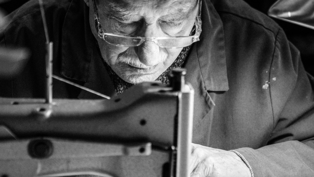 Close-up of an elderly artisan meticulously working with a sewing machine.