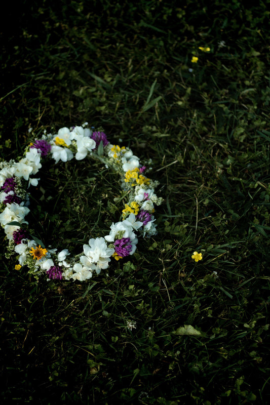 Flower crown with white, yellow, and purple blossoms on green grass outdoors
