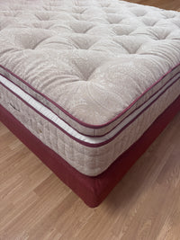Close-up of a luxury tufted mattress with paisley pattern and red side panels on wooden floor