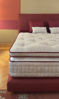 Luxury handmade mattress with red upholstered bed frame and headboard.